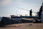 Pescador en la escollera Sarandí y un barco saliendo del puerto - Foto #79164